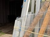 a pile of windows sitting on a pallet in front of a building