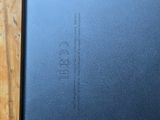 a close up of the back of a black phone on a wooden table