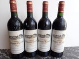 four bottles of wine are lined up on a table