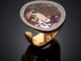 a close up of a ring with a purple stone and diamonds