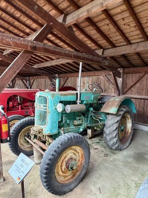 un tracteur qui se trouve dans une grange avec d'autres tracteurs