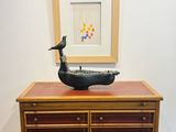 une commode en bois surmontée d'une sculpture d'oiseau
