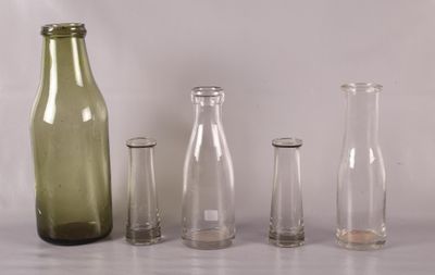 trois bouteilles vides et deux vases en verre vides posés sur une table