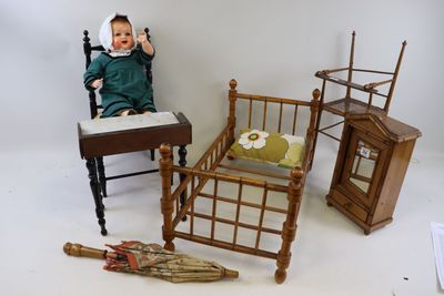 une poupée assise sur une chaise à côté d'un lit