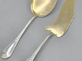 two spoons and a knife on a table with a gray background