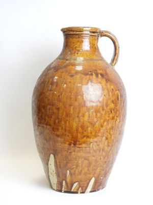 a brown vase that is sitting on a white surface