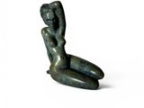statue d'une femme assise, le dos appuyé contre une surface blanche