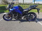 a blue motorcycle parked in a parking lot next to a fence