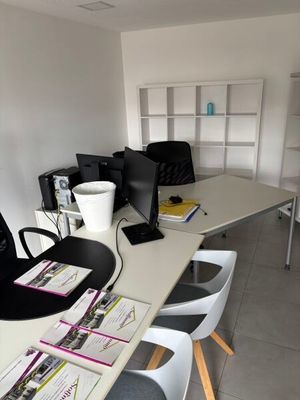 un bureau avec un ordinateur et plusieurs chaises dans la pièce