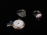 trois bagues et une montre posées sur une surface noire