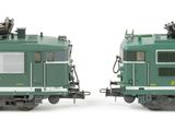 two green trains sitting side by side on a white surface