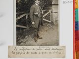 an old photo of a man in a suit and tie standing in front of a fence
