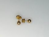 une petite paire de boucles d'oreilles en or posée sur une surface blanche