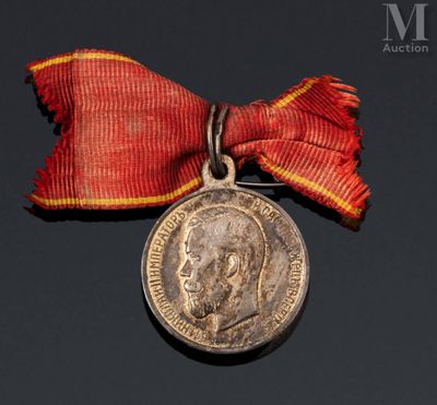 une vieille médaille entourée d'un ruban rouge et une médaille en argent entourée d'un ruban rouge