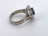 a close up of a diamond and sapphire ring on a white surface