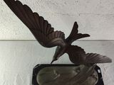 statue of a bird on a marble base on a white surface