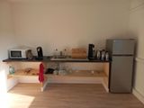 une petite cuisine équipée d'un réfrigérateur, d'un micro-ondes et d'une cafetière
