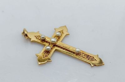 une image représentant une croix en or ornée d'une perle