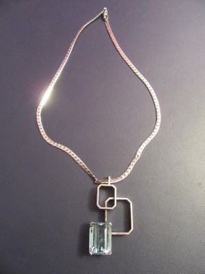a silver necklace with a green stone hanging from it