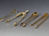 cinq cuillères en argent et un repose-cuillère sur une table
