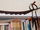 une étagère sur laquelle sont posés des livres et une faux en métal