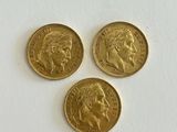 three gold sovereigns on a white surface