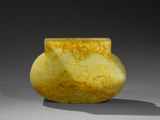 un vase jaune et blanc posé sur une table, sur une surface grise