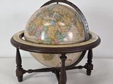 un vieux globe terrestre posé sur un socle, avec un fond blanc