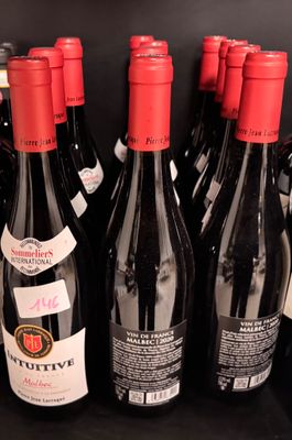 bottles of red wine are lined up on a shelf in a store