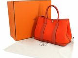 an orange handbag sitting next to an orange box on a white surface