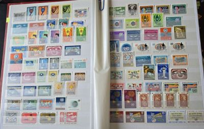 un livre ouvert, sur lequel sont collés des timbres et dans lequel se trouve un stylo