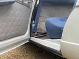 a blue seat in the door of a white car