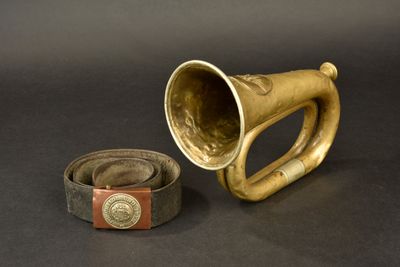 a brass horn and a leather belt on a black background
