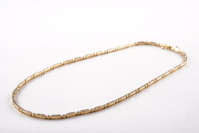 a close up of a gold necklace on a white surface