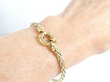 someone is wearing a gold bracelet with a chain on their wrist