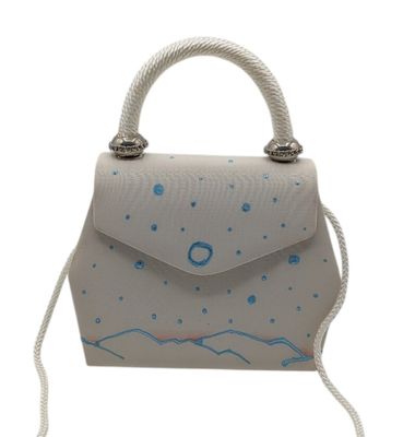 Le petit sac à main blanc est orné d'un motif bleu et blanc.
