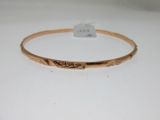 gros plan d'un bracelet en or sur une surface blanche