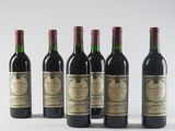 six bottles of wine are lined up on a white surface