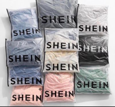 une pile de chemises de différentes couleurs posée sur une surface blanche