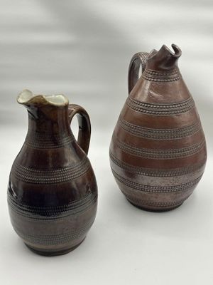 deux vases bruns posés l'un à côté de l'autre sur une surface blanche