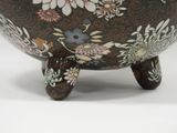 a brown bowl with flowers on it sitting on a stand