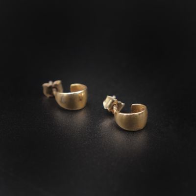 une paire de boucles d'oreilles en or sur une surface noire