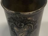 a silver cup with a design on it on a white surface