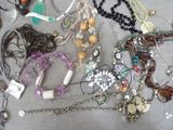 many different types of necklaces and bracelets on the table