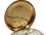 a gold pocket watch sitting on top of a wooden table