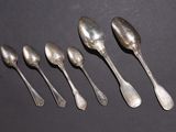 six spoons are lined up in a row on a black surface
