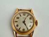 a gold watch with a white face on a white surface