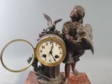 une statue représentant un homme tenant une horloge sur laquelle est posé un oiseau