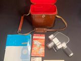 a brown case with a camera and other items on a table