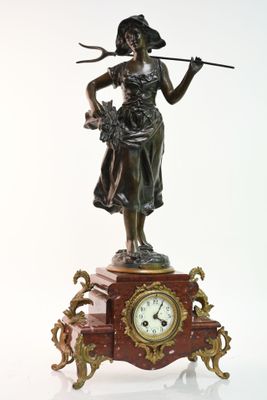 une statue représentant une femme tenant un bâton et une horloge